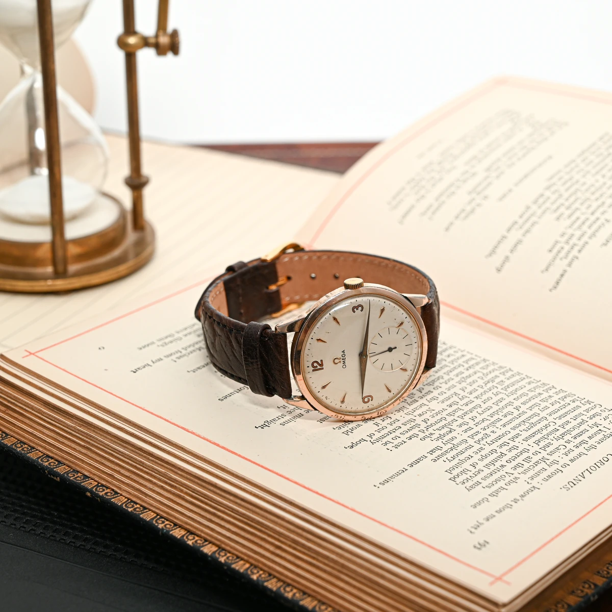 Vintage ρολόι χειρός Omega με κάσα σε ροζ χρυσό χρώμα, πάνω σε παλιό βιβλίο